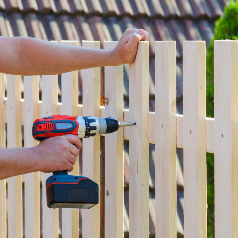 An image of person working on a privacy fence installation